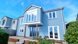 A two-story residential building with a blue exterior, a front porch, and a small garden area.