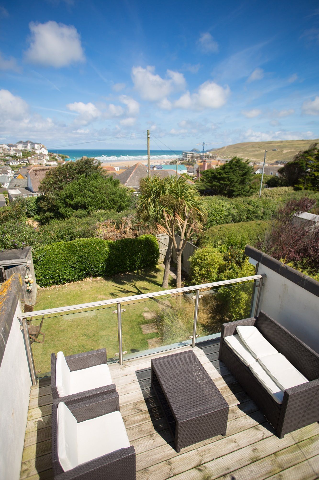 A balcony with wicker furniture overlooking a coastal town.