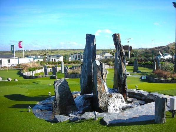 A golf course with a rocky centerpiece, surrounded by well-maintained grass and stone structures.