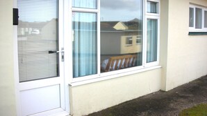 A building with a white door and windows, a balcony with a wooden railing, and a number '151' above the door. - Chalet on Perran Sands, Haven holiday park (Perranporth)