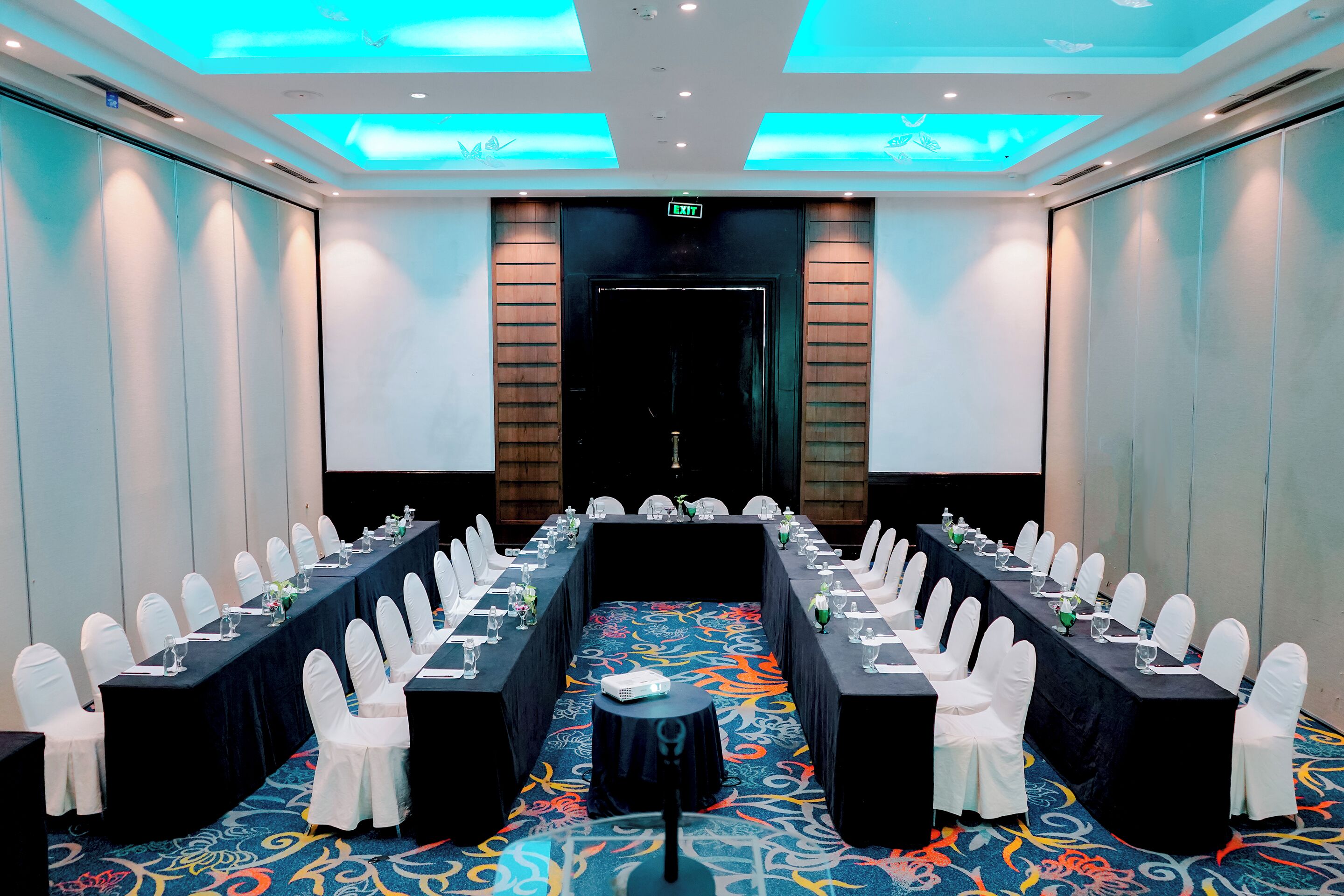A conference room with a long table, white chairs, and a projector.