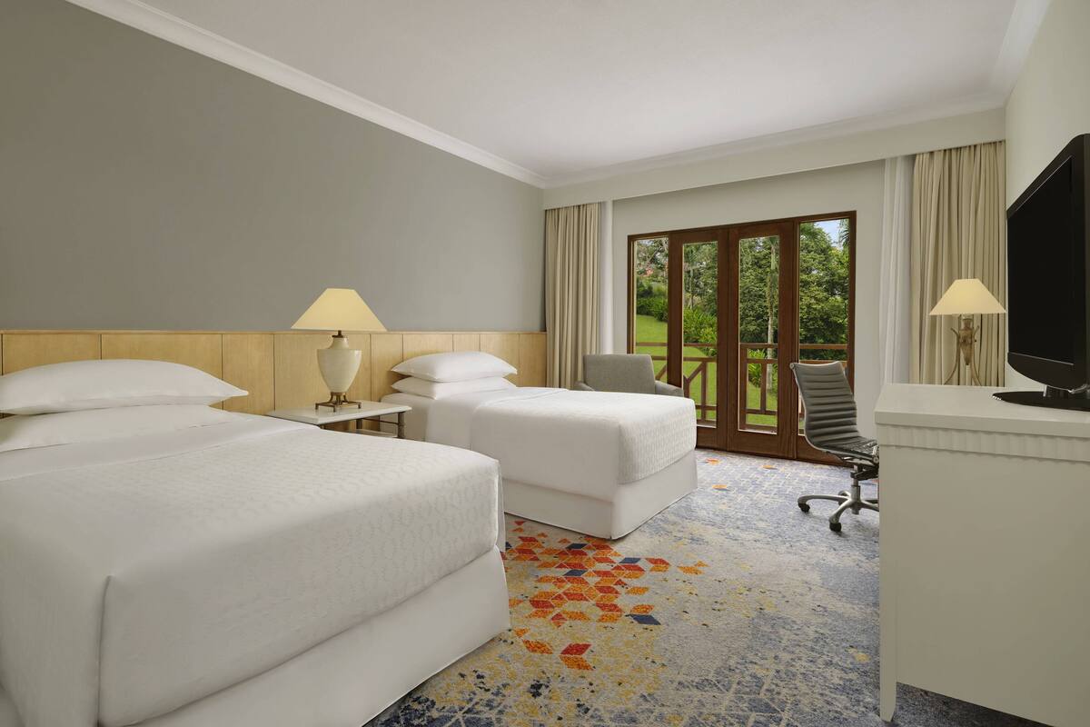 Una habitación de hotel con dos camas, un escritorio, una silla y un televisor.