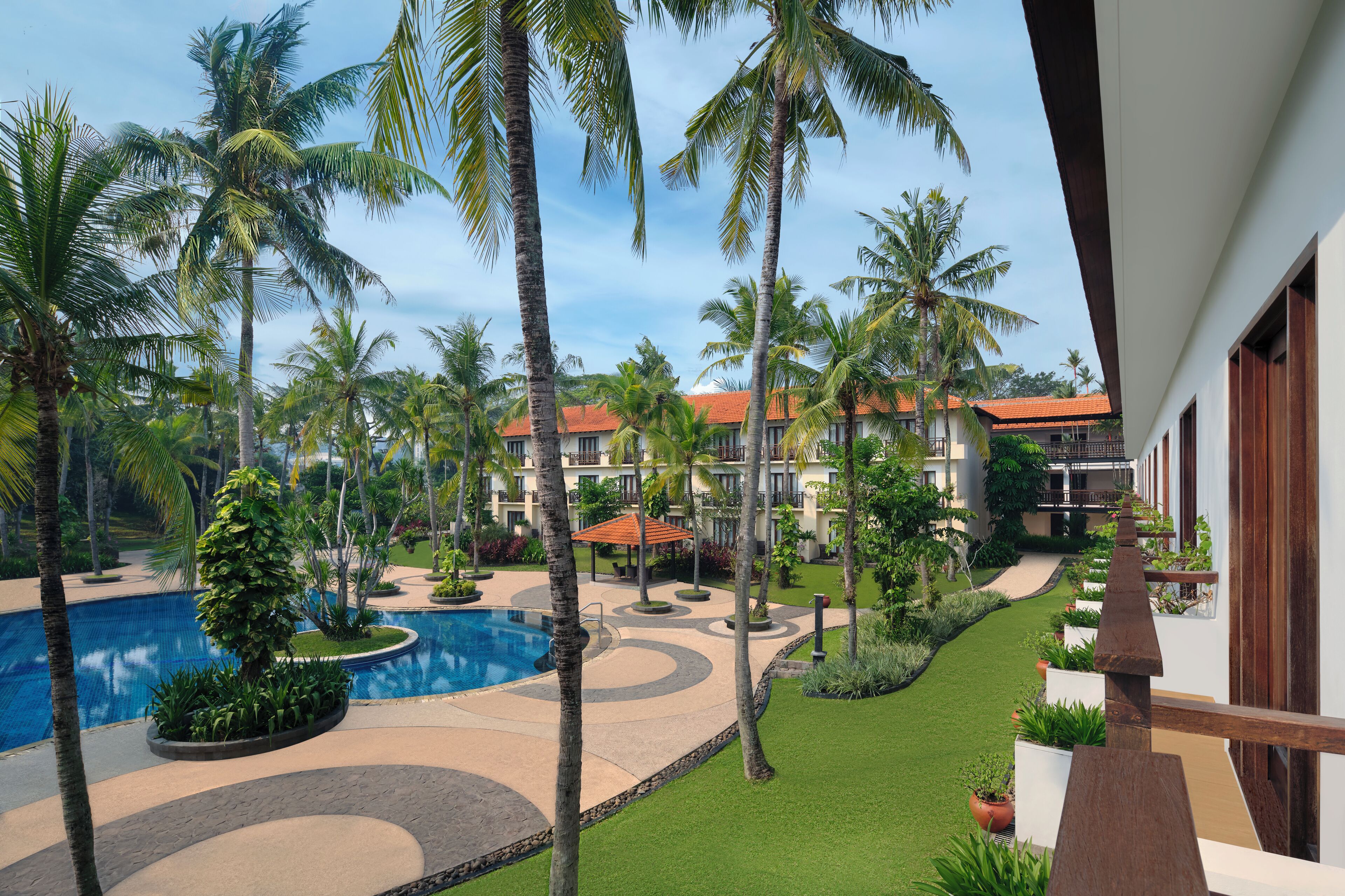 Un resort con piscina, palmeras y césped bien cuidado.