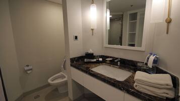 A bathroom with a marble sink, a toilet, a mirror, and a towel rack.