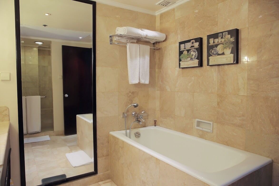 Une salle de bain moderne avec une grande baignoire, un miroir et deux tableaux encadrés accrochés au mur.
