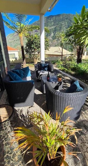 Um pátio externo com móveis de vime e plantas em vasos.
