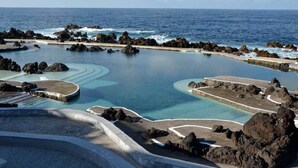 A coastal resort with a large infinity pool surrounded by rocky terrain and the ocean. - Casa Brisa - by PrimeStayMadeira (São Vicente)