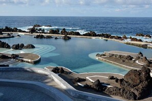 A coastal resort with a large infinity pool surrounded by rocky terrain and the ocean. - Casa Brisa - by PrimeStayMadeira (São Vicente)