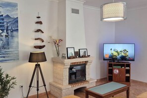 Een woonkamer met een open haard, een televisie en een lamp.