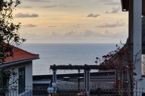A coastal view with a building, a pergola, and a fence. - Casa Brisa - by PrimeStayMadeira (São Vicente)