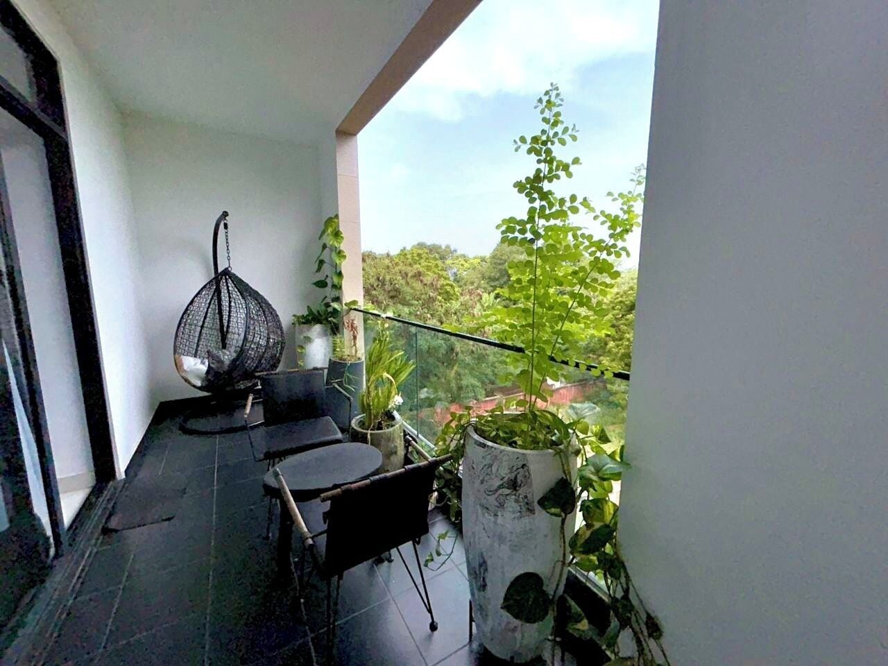 A balcony with a table and chairs, potted plants, and a hanging chair.