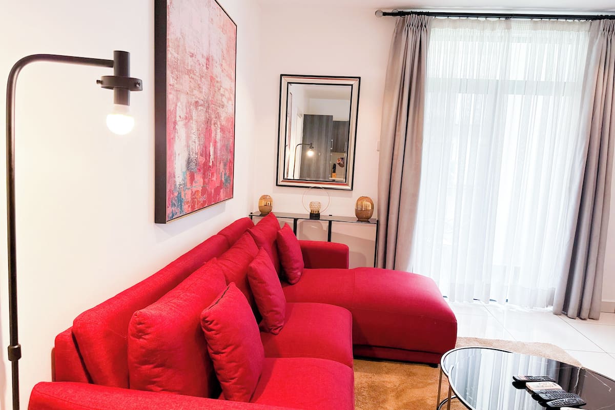Una sala de estar moderna con un sofá seccional rojo, una mesa de centro de vidrio y una lámpara de pie.