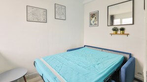 A bedroom with a bed, a small table, and two framed artworks on the wall. - Studio overlooking the rooftops of Paris, 2 minutes from the metro (Paris)