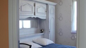 A bedroom with a bed, white wardrobe, and patterned wallpaper.