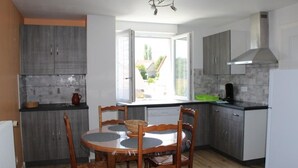 A modern kitchen with grey cabinets, a round wooden table with chairs, and a window providing natural light.