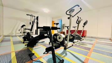 Ein Fitnessstudio mit verschiedenen Trainingsgeräten, darunter Laufband, Ergometer und Kraftmaschine.