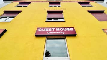 Ein gelbes Gebäude mit einem scharlachroten Schild, auf dem „GUEST HOUSE University“ und die Registrierungsnummer „MDCCCLXXXVIII“ steht.