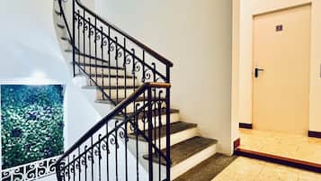 Un escalier orné de rampes noires et d’une main courante en bois, menant à une porte portant le numéro 2.
