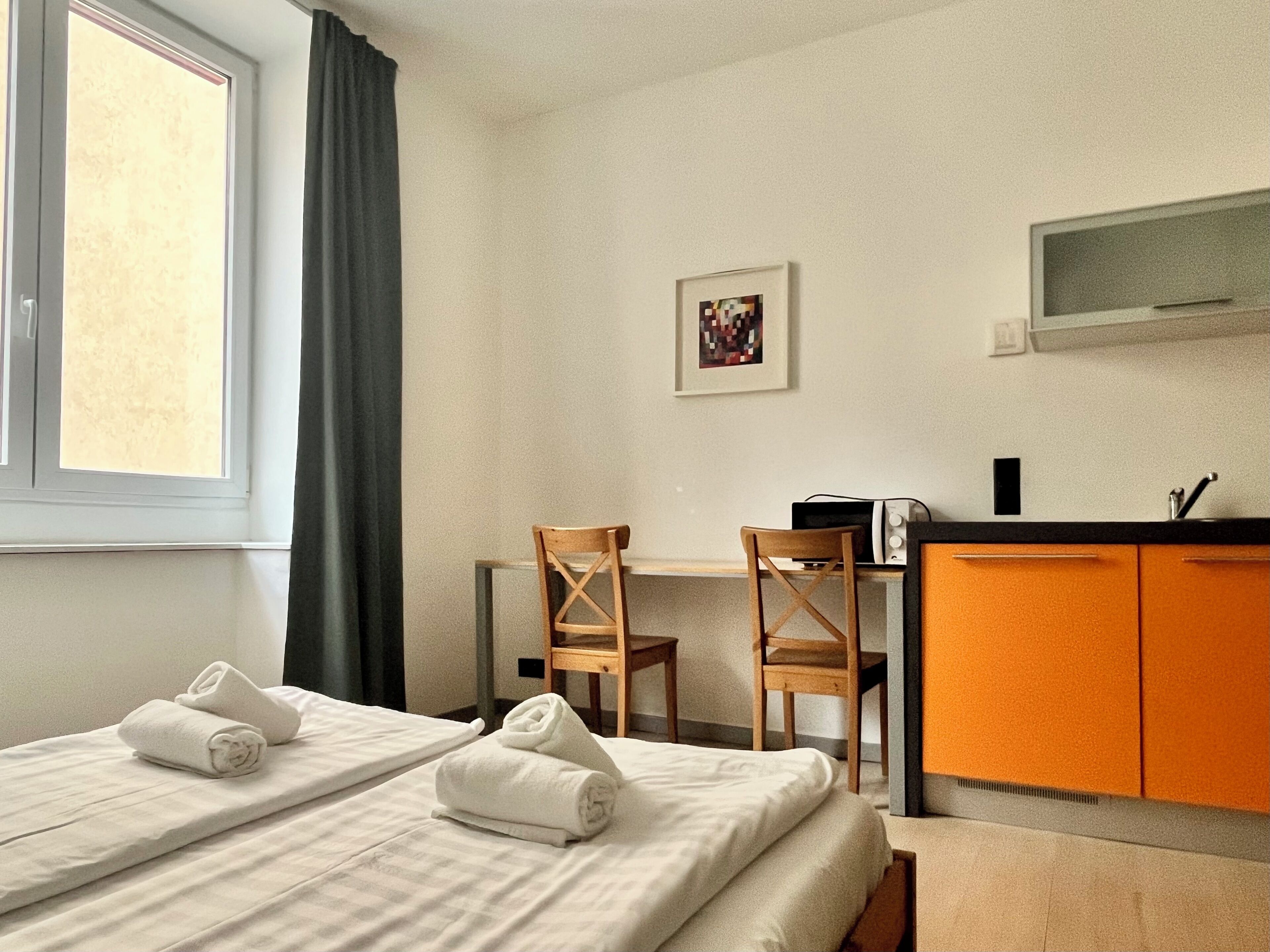 Habitación de hotel con dos camas, un escritorio, una silla y un televisor.