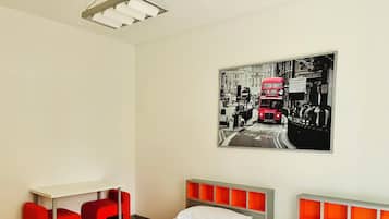 Ein Hotelzimmer mit zwei Betten, einem Schreibtisch und roten Stühlen.