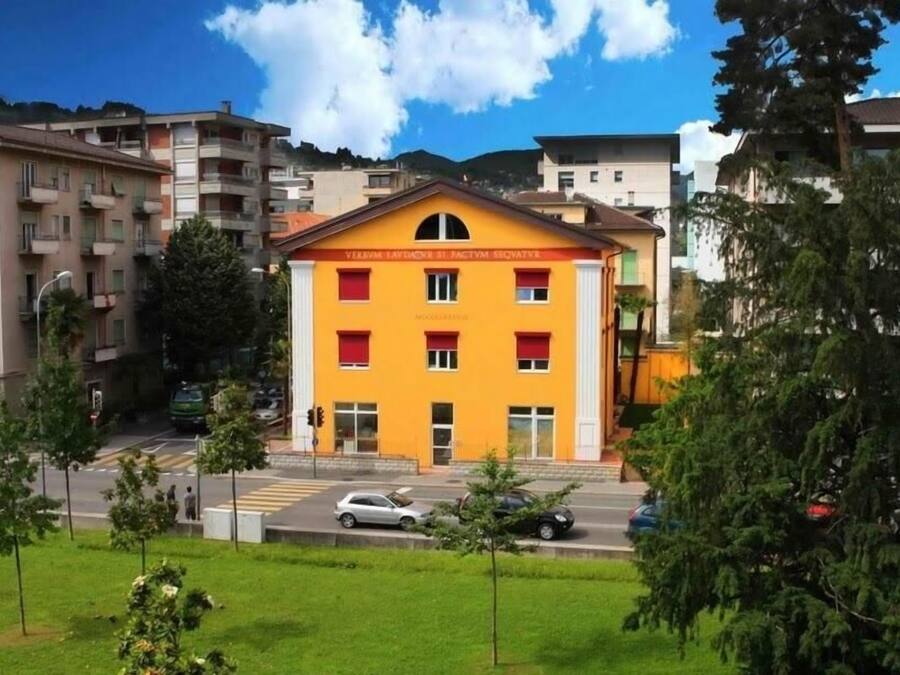 Un edificio amarillo con ventanas rojas y un letrero en un idioma extranjero.
