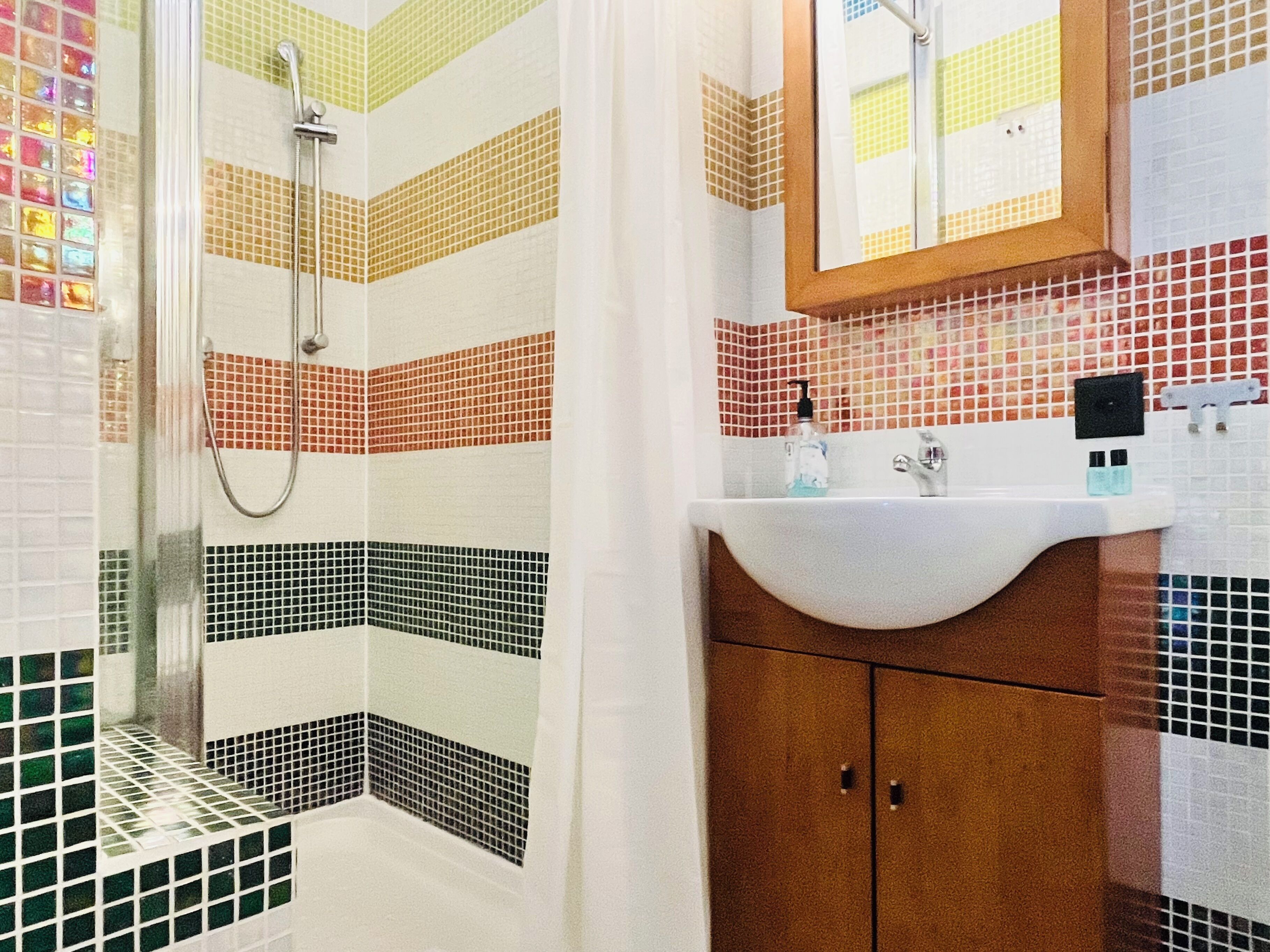 Ein Badezimmer mit Dusche, Waschbecken und Spiegel.