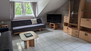 Un soggiorno moderno con divano, televisore e mobili contenitori in legno.