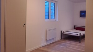 Una habitación con cama, radiador, ventana y puerta.