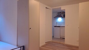 Un pasillo con una cama, un armario y una pequeña cocina.
