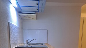 Una cocina compacta con encimera de madera, un lavamanos y un refrigerador empotrado.