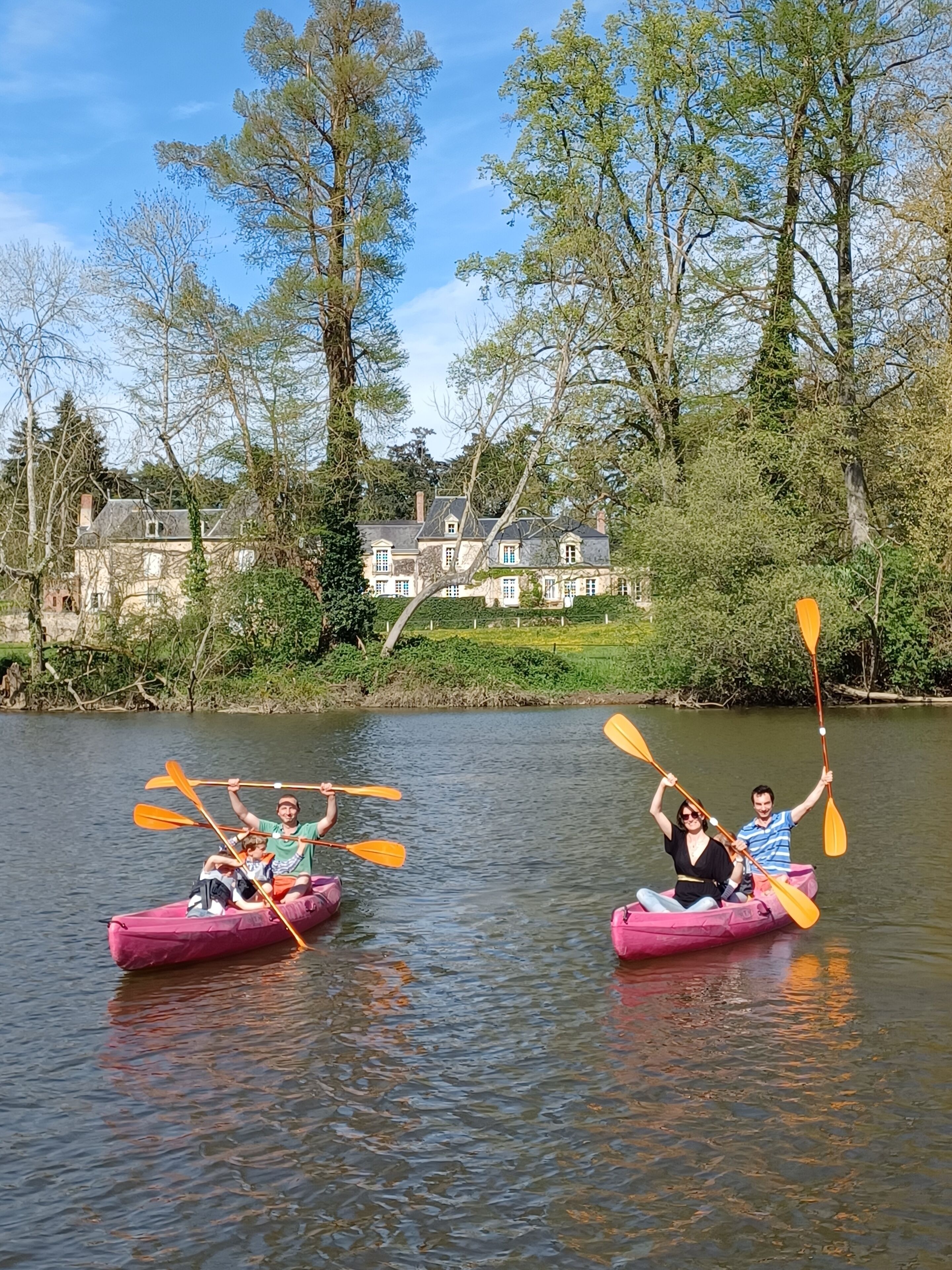 Dos personas en kayaks rosados en un río tranquilo, remando.