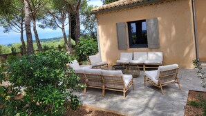 A rustic villa with a patio featuring wicker furniture and a view of the countryside. - Bastide provençale amidst vineyards with swimming pool and lovely view - Sleeps 12 (Caromb)