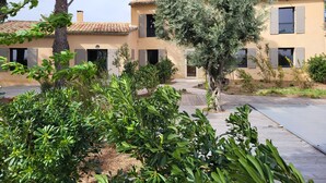 A building with a tiled roof and multiple windows, surrounded by greenery and trees. - Bastide provençale amidst vineyards with swimming pool and lovely view - Sleeps 12 (Caromb)