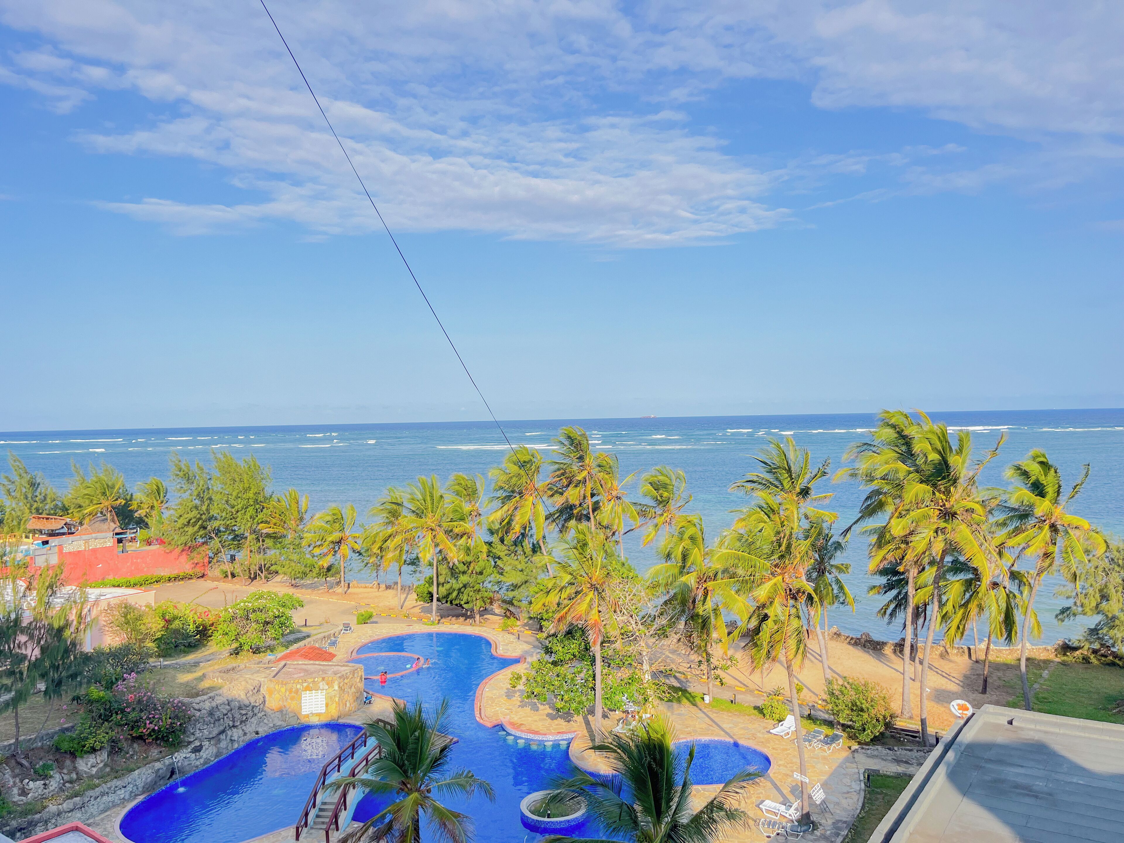 Un resort con piscina, palmeras y vistas al océano.