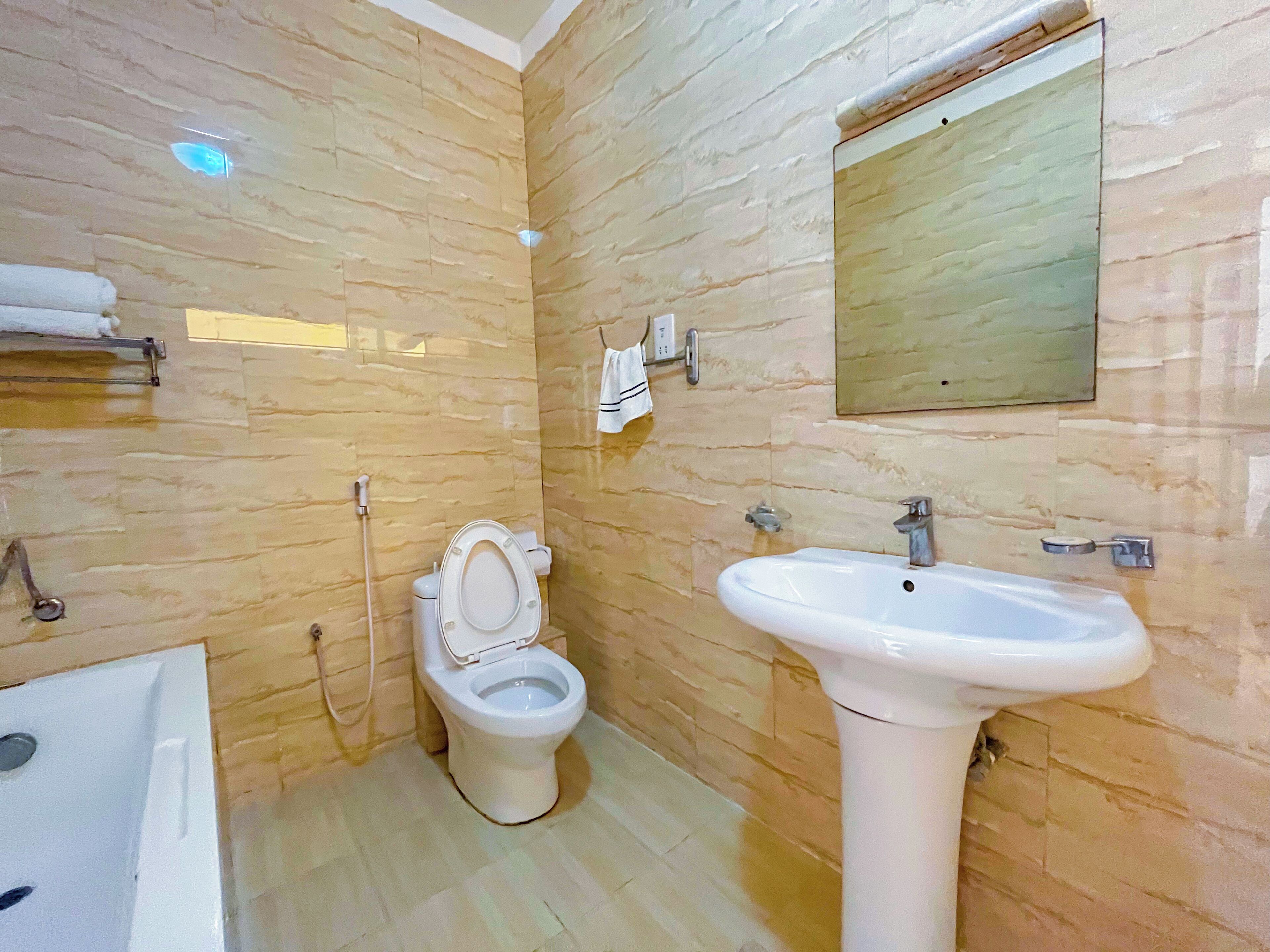A bathroom with a toilet, sink, and mirror.