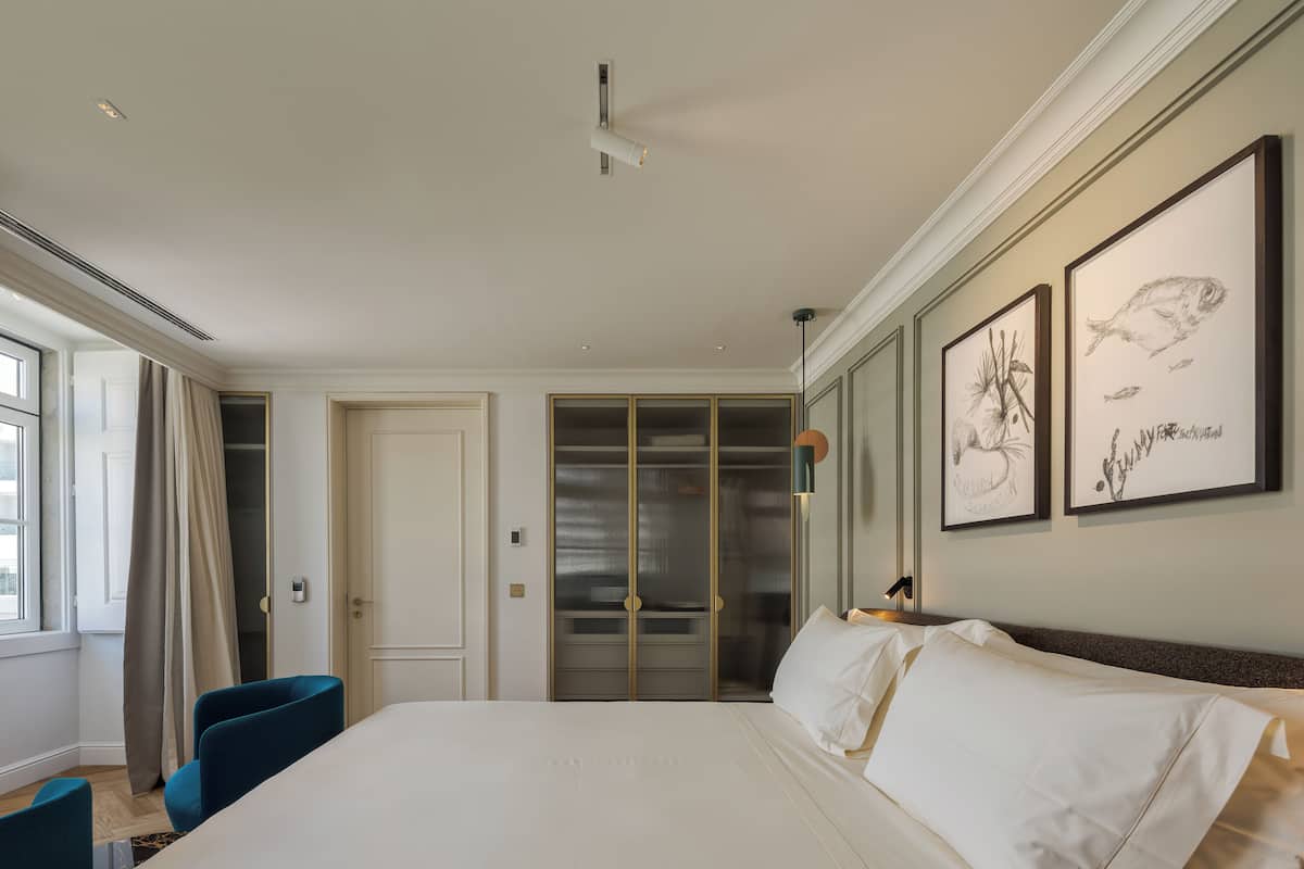 A hotel room with a large bed, a wardrobe, a desk, and a window with curtains.