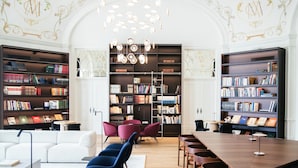 Une bibliothèque avec des étagères, un canapé blanc, des chaises bleues et une table en bois.
