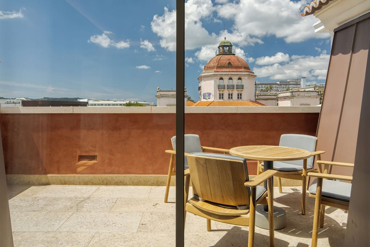 A rooftop terrace with a table and chairs, a view of a building with a dome and a clock tower, and a clear sky.