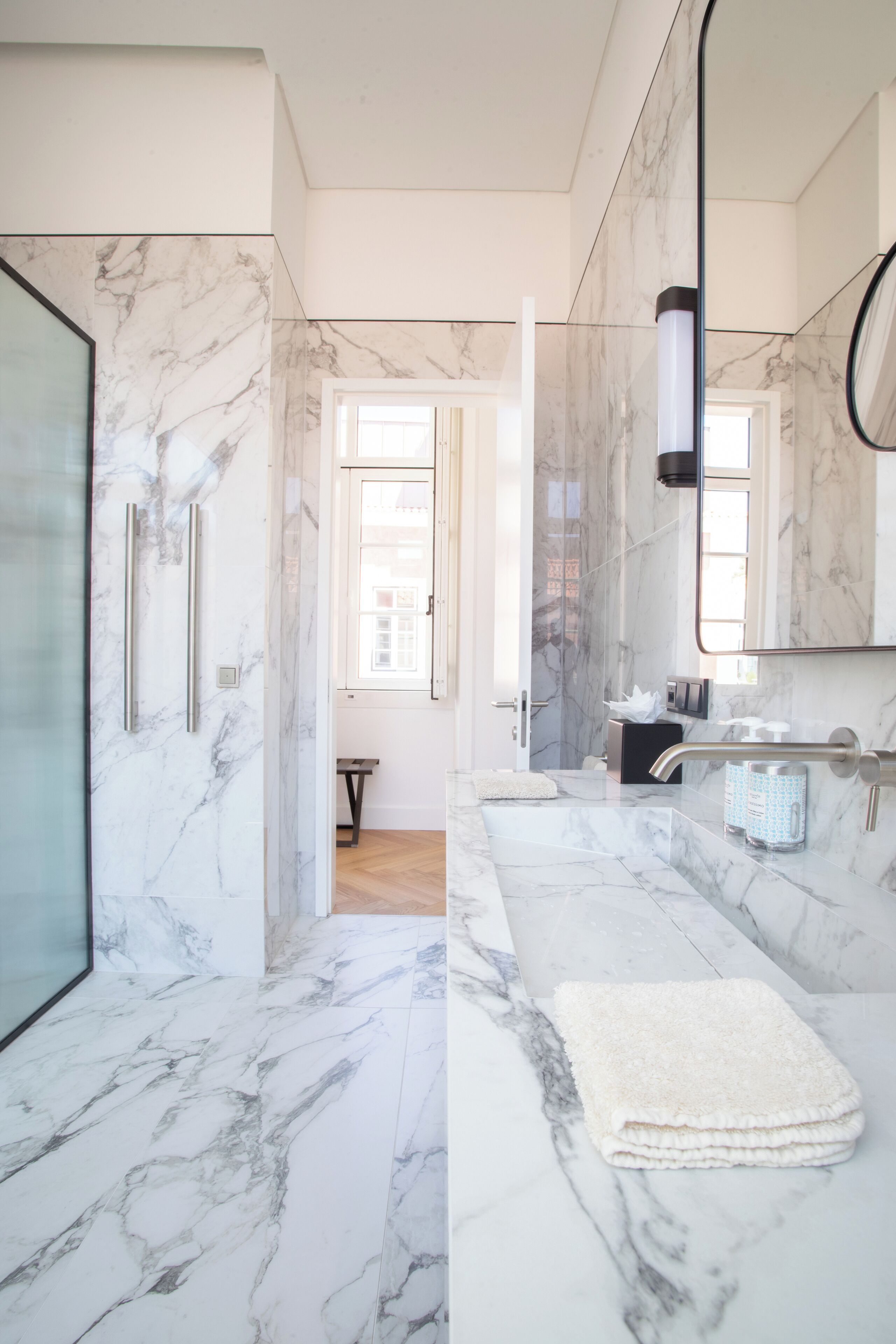 Une salle de bain moderne avec un sol en marbre, une douche en verre, un meuble-lavabo avec un miroir et une serviette posée sur le comptoir.