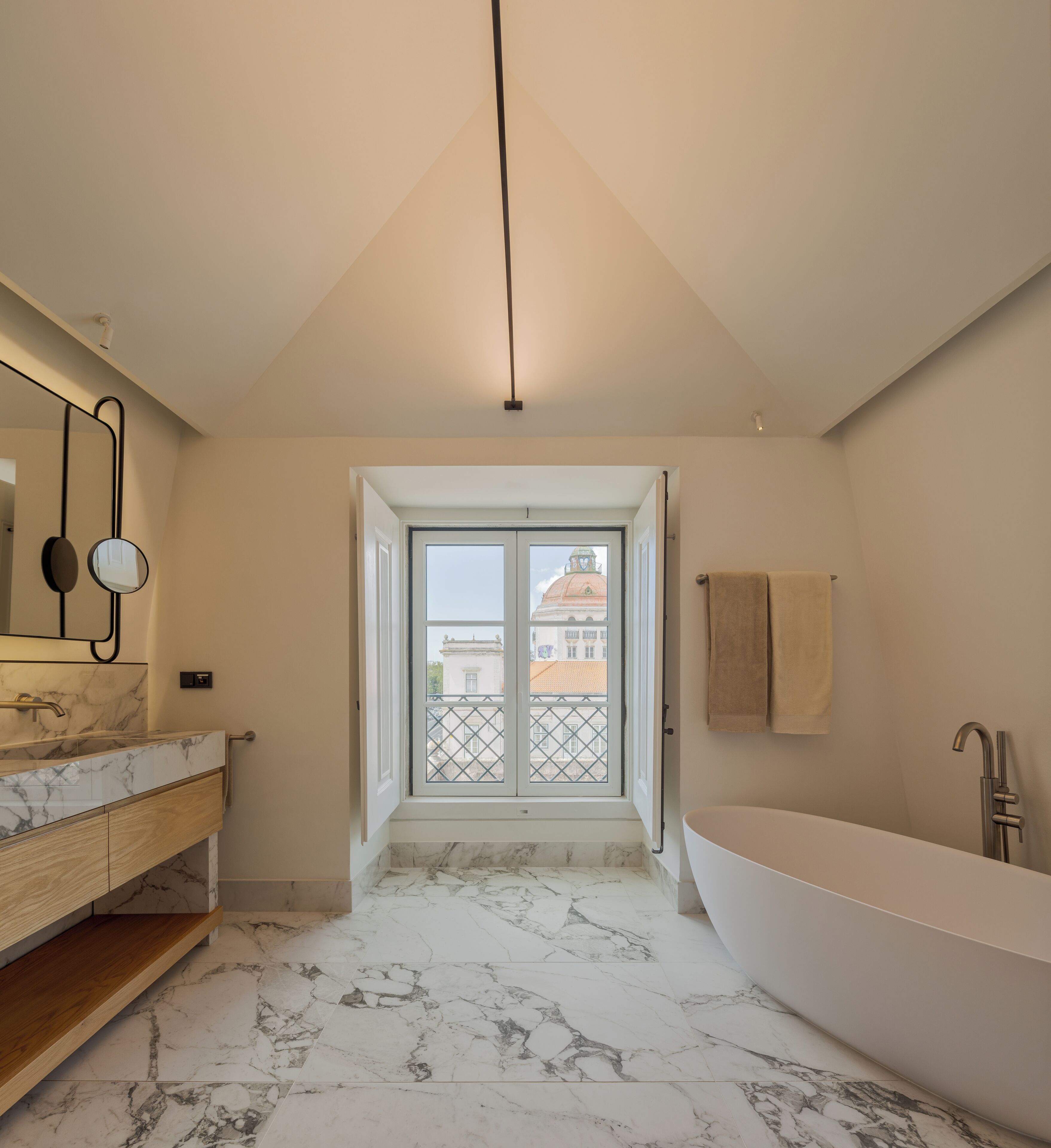 A modern bathroom with a freestanding bathtub, a vanity with a marble countertop, and a large mirror.