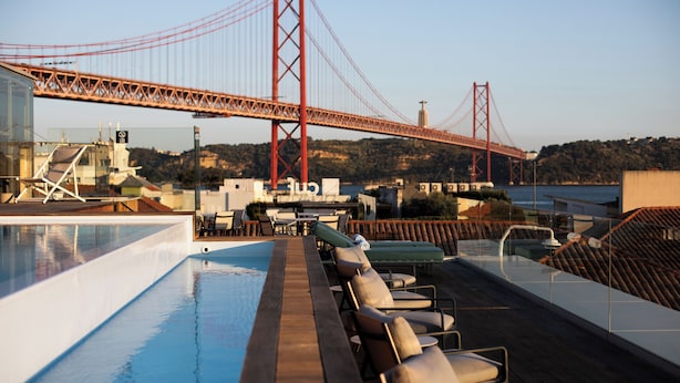 Un espace aménagé au bord de la piscine, avec des chaises longues et une vue sur un pont.