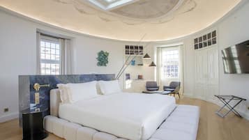 Une chambre moderne avec un grand lit, une fenêtre de toit, une télévision et un bureau avec des chaises.