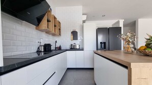 A modern kitchen with white cabinetry, black countertops, and a wooden island.