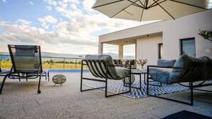 A modern outdoor patio with a table, chairs, and a large umbrella.
