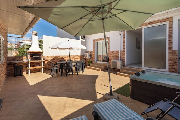 An outdoor patio with a barbecue grill, seating area, and a hot tub. - Zurrinha Holidays With Jacuzzi (Loulé)