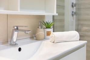 A bathroom with a white sink, a towel, a potted aloe vera plant, and a soap dispenser. - Zurrinha Holidays With Jacuzzi (Loulé)