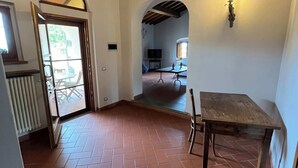An open-plan living area with a tiled floor, a wooden table, and a TV in the background. - Colorino-huge and splendid apartment (Reggello (FIRENZE))