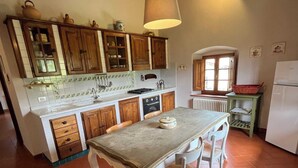 A kitchen with wooden cabinets, a tiled backsplash, a central island with chairs, and a hanging light fixture. - Colorino-huge and splendid apartment (Reggello (FIRENZE))
