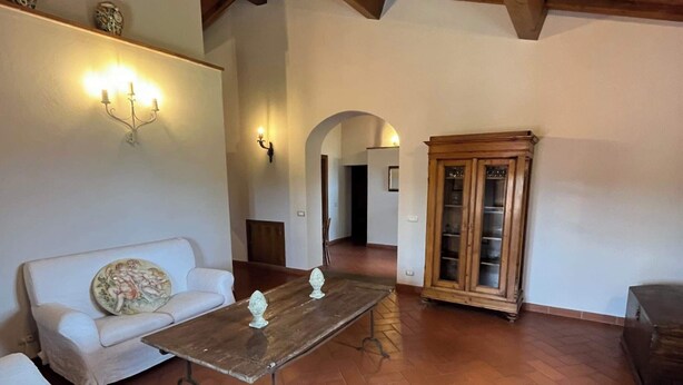 A spacious living area with a wooden ceiling, a white sofa, a wooden coffee table, and a cabinet with glass doors. - Colorino-huge and splendid apartment (Reggello (FIRENZE))
