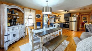 Una cocina acogedora con armarios de madera, una mesa de comedor y un refrigerador.
